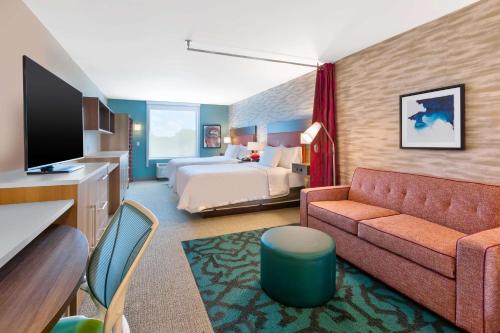 Habitación de hotel con cama y sofá en Home2 Suites By Hilton Grand Blanc Flint, Mi, en Grand Blanc