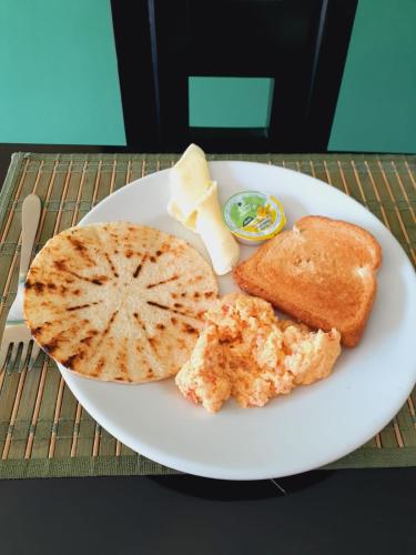 a white plate of food with bread and cheese at Ayenda Mountain Hostels Manizales in Manizales
