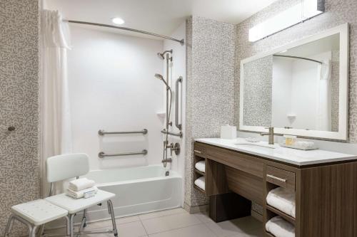a bathroom with a sink and a tub and a mirror at Home2 Suites by Hilton New Brunswick, NJ in New Brunswick