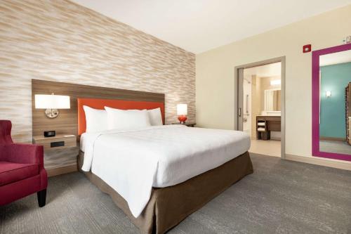 a bedroom with a large bed and a red chair at Home2 Suites by Hilton New Brunswick, NJ in New Brunswick