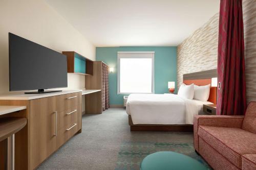 a hotel room with a bed and a flat screen tv at Home2 Suites by Hilton New Brunswick, NJ in New Brunswick