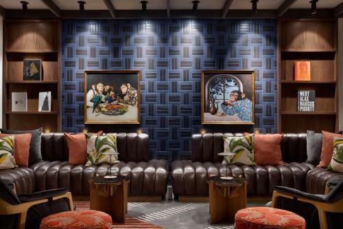 a room with leather couches and paintings on a wall at 106 Jefferson Huntsville, Curio Collection by Hilton in Huntsville