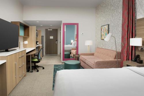 a hotel room with a bed and a desk at Home2 Suites by Hilton Fort Myers Airport in Fort Myers