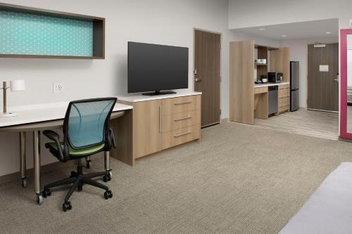 an office with a desk with a television and a chair at Home2 Suites by Hilton Fort Myers Airport in Fort Myers