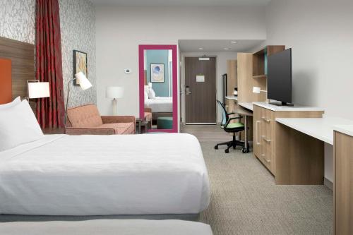 a hotel room with a white bed and a desk at Home2 Suites by Hilton Fort Myers Airport in Fort Myers