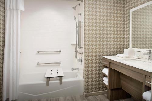 a bathroom with a tub and a shower and a sink at Home2 Suites by Hilton Fort Myers Airport in Fort Myers