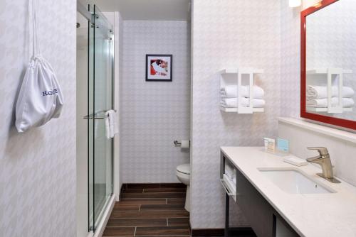 a bathroom with a toilet and a sink and a mirror at Hampton Inn & Suites Greensboro Downtown, Nc in Greensboro