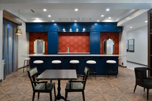 a restaurant with a bar with chairs and a table at Hampton Inn & Suites Greensboro Downtown, Nc in Greensboro