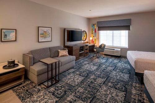 um quarto de hotel com uma cama, um sofá e uma televisão em Hampton Inn & Suites Huntington Downtown, Ny em Huntington