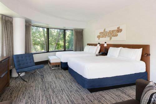 a hotel room with two beds and a chair at Hilton Fairfax, Va in Fairfax