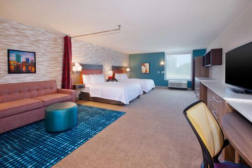 a hotel room with a bed and a couch at Home2 Suites By Hilton Grand Rapids South in Byron Center