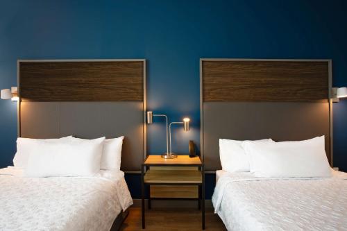 two beds in a hotel room with blue walls at Tru By Hilton Port St Lucie Tradition in Port Saint Lucie