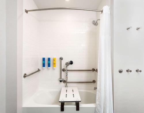 ein Badezimmer mit einer Badewanne und einer Dusche mit einer Bank in der Unterkunft Tru By Hilton Port St Lucie Tradition in Port Saint Lucie