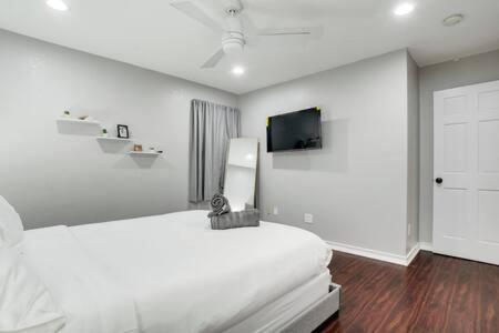 1 dormitorio blanco con 1 cama y TV de pantalla plana en Villa in Grand Prairie with pool sauna hot tub and more, en Grand Prairie