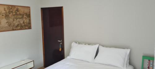 a bedroom with a white bed and a black door at Quarto Luz in Jaraguá do Sul