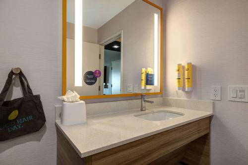 a bathroom with a sink and a large mirror at Tru By Hilton Galveston, Tx in Galveston