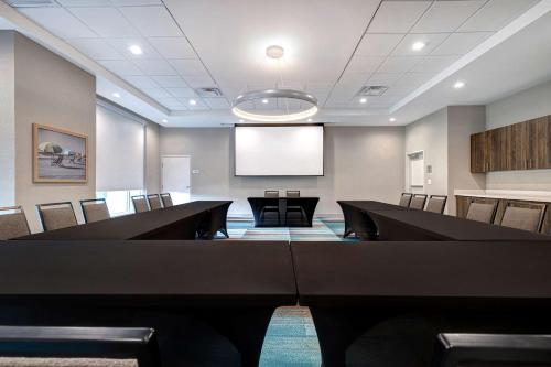 a conference room with black tables and chairs and a screen at Tru By Hilton Galveston, Tx in Galveston