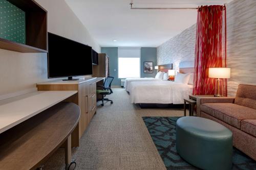 um quarto de hotel com uma cama e uma televisão de ecrã plano em Home2 Suites Galveston, Tx em Galveston