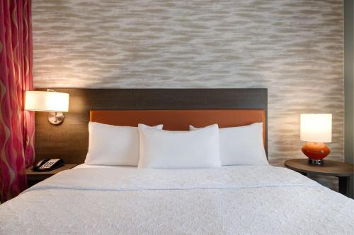 a bedroom with a bed with white pillows and two lamps at Home2 Suites Galveston, Tx in Galveston