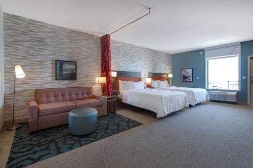 a hotel room with a bed and a couch at Home2 Suites Galveston, Tx in Galveston