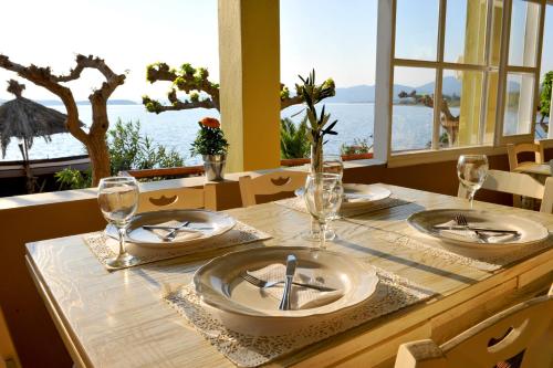 a table with plates and glasses on it with a view of the ocean at Venus Beach Hotel in Nea Stira