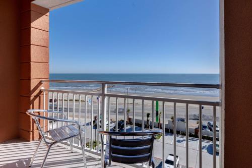 a balcony with a table and chairs and the beach at Home2 Suites Galveston, Tx in Galveston