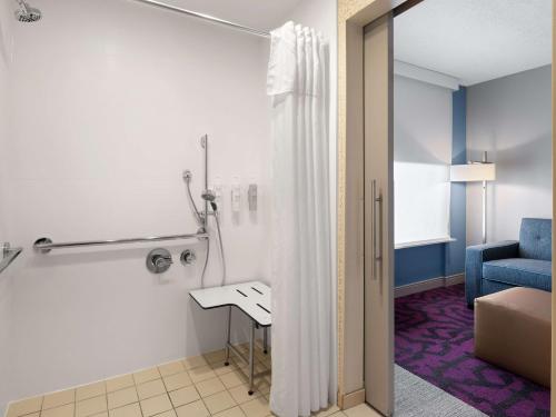 a bathroom with a shower with a table and a chair at Home2 Suites by Hilton Indianapolis - Keystone Crossing in Indianapolis