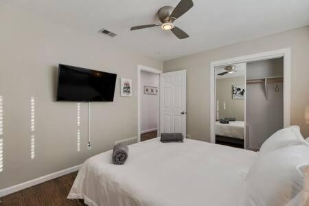 a bedroom with a white bed and a flat screen tv at DFW Lux House with Huge Backyard Pool Jacuzzi Bbq Cinema etc in Farmers Branch