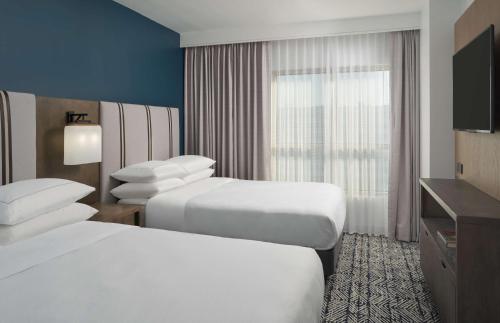 a hotel room with two beds and a television at The Chifley Houston, Tapestry Collection by Hilton in Houston