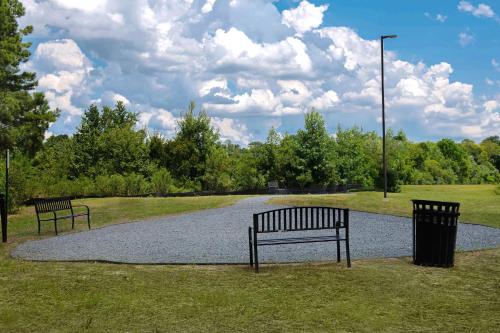 two benches sitting in a park on a gravel road at Home2 Suites By Hilton Fayetteville North in Fayetteville