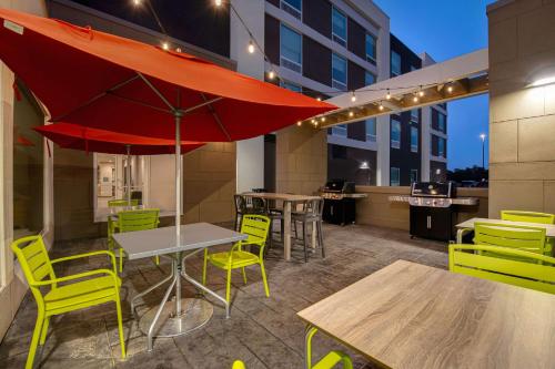 a patio with a table and chairs and an umbrella at Home2 Suites By Hilton Fayetteville North in Fayetteville
