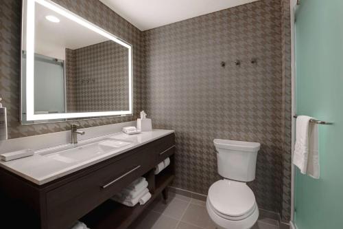 a bathroom with a sink and a toilet and a mirror at Home2 Suites By Hilton Fayetteville North in Fayetteville