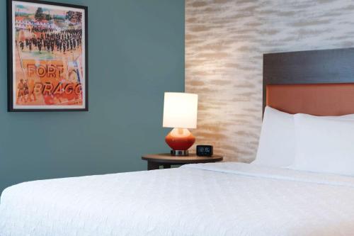 a bedroom with a bed and a lamp on a table at Home2 Suites By Hilton Fayetteville North in Fayetteville