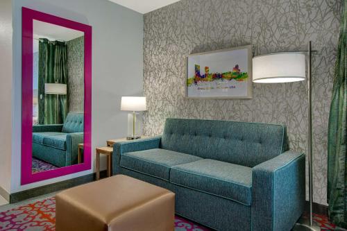 a living room with a blue couch and a mirror at Home2 Suites By Hilton Grand Rapids Airport in Kentwood