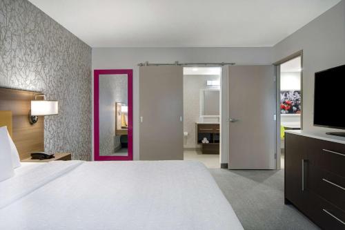 a hotel room with a bed and a flat screen tv at Home2 Suites By Hilton Grand Rapids Airport in Kentwood