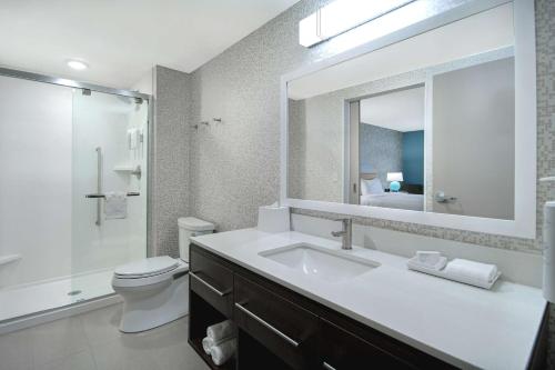 Home2 Suites By Hilton Grand Rapids Airport في Kentwood: حمام مع حوض ومرحاض ومرآة