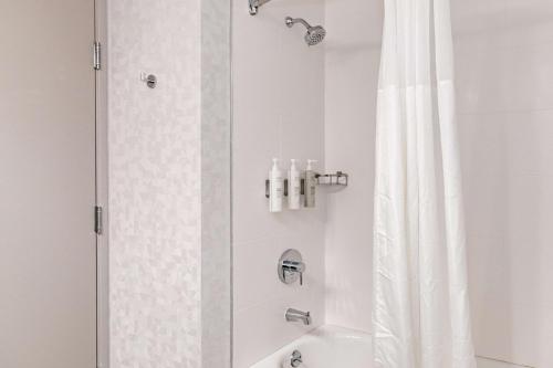 a bathroom with a shower with a white shower curtain at Hampton Inn & Suites By Hilton- Newark Airport Elizabeth in Newark