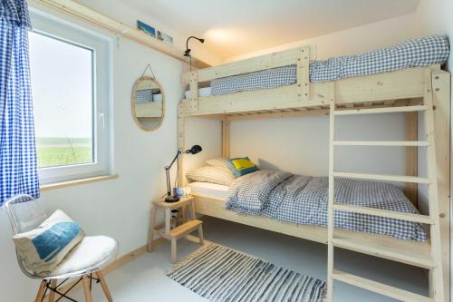 a bedroom with bunk beds and a chair and a window at Herthaquelle Lazy "Milou" in Garz-Rügen
