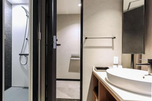 ein Bad mit einem Waschbecken und einer Glastür in der Unterkunft Best Western Plus Nagoya Sakae in Nagoya