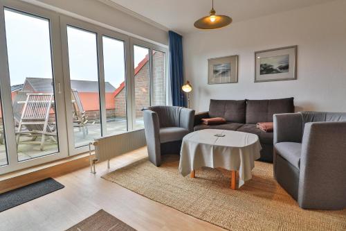a living room with a couch and chairs and windows at Seemannskojen Backbord in Langeoog