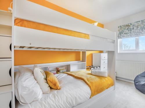 a bedroom with a white bunk bed with yellow walls at Vine Cottage 