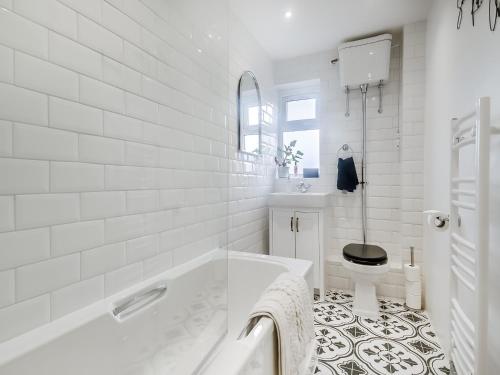 a white bathroom with a tub and a toilet at Vine Cottage 