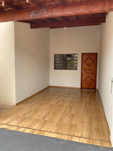 an empty room with a wooden floor and a door at Casa de temporada in Olímpia