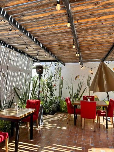 a patio with red chairs and tables and a wooden ceiling at Santa Madre B&B in San Luis Potosí