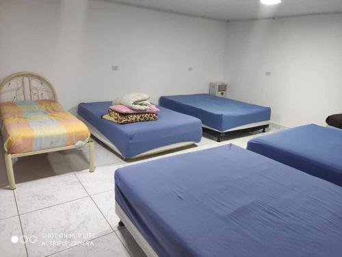 a room with three blue beds and a chair at Chácara de Lazer 2 Lagoas in Nova Esperança