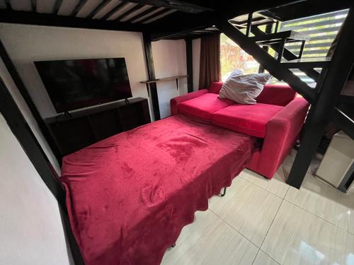 ein Wohnzimmer mit einem roten Sofa und einem TV in der Unterkunft Studio B Loft M&K's Guesthouse in Dauis