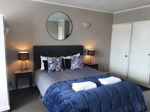 - une chambre avec un grand lit bleu et un miroir dans l'établissement Aorangi Motel, à Fairlie