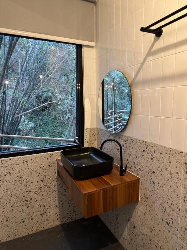 a bathroom with a black sink and a mirror at Bwalk Hotel & Villa Malang in Sengkaling