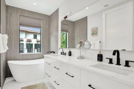 La salle de bains est pourvue de 2 lavabos et d'un grand miroir. dans l'établissement New 4BR w Pool Walk to Las Olas 5mins to Beach, à Fort Lauderdale