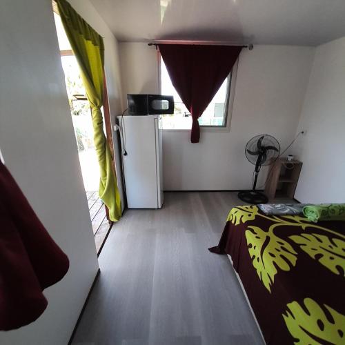 a small room with a bed and a refrigerator at Nuutea lodge 2 in Avatoru